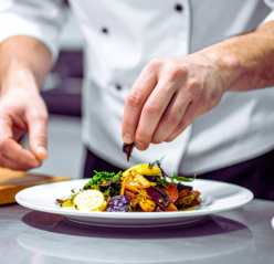 A woman setting tables in a restaurant, arranging chairs and placing utensils for upcoming diners.
